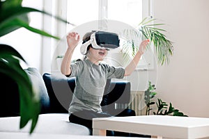 Happy girl with virtual reality headset sitting on sofa