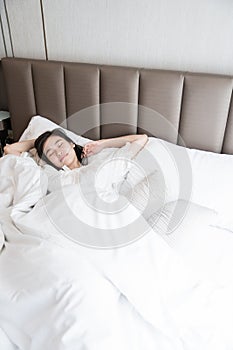 Happy girl wake up in the morning on cozy and comfortable bed cover with white blanket / Happy concept / non-sleeping trouble
