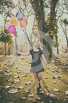 Happy girl walking alone with ballons and smiling