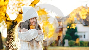 Happy girl walking in autumn park. Little girl wearing warm knitted sweater