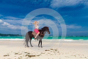 Happy girl walking with horse on a tropical beach