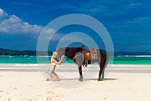 Happy girl walking with horse on a tropical beach