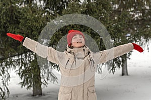 Happy girl warm winter clothes enjoys nature in winter forest. Young woman walk in snow-covered park