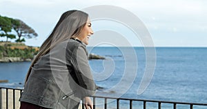 Happy girl watching the sea from a balcony