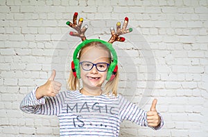 Happy girl wearing Christmas raindeer horns and eyeglasses with her thumbs up, poor eyesight correction