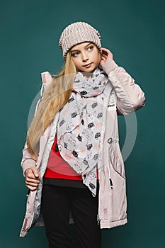 Happy girl wearing in jeans, boots, a warm jacket and hat. Cropped portrait of a teenage blonde model girl in modish