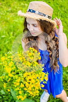 Happy girl wearing straw hat harvesting flowering herbs in field