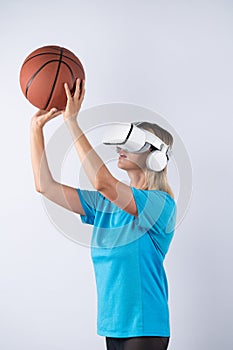 Happy girl wearing visual reality glasses and holding basketball. Contraption.