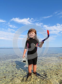 happy girl with wetsuit, masks and snorkels at the s