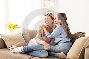 Happy girl whispering secret to her mother at home