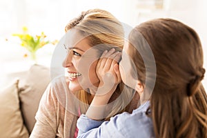 Happy girl whispering secret to her mother at home