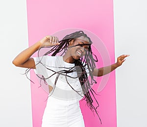 Happy girl in white overall dancing outdoors at a wall