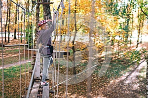 Happy girl, woman, climbing gear in an adventure, rope road, insurance, attraction, amusement park, active recreation, autumn