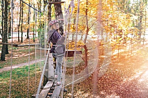 Happy girl, woman, climbing gear in an adventure, rope road, insurance, attraction, amusement park, active recreation, autumn