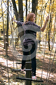 Happy girl, woman, climbing gear in an adventure, rope road, insurance, attraction, amusement park, active recreation, autumn