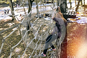 Happy girl, woman, climbing gear in an adventure, rope road, insurance, attraction, amusement park, active recreation, autumn