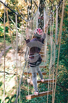 Happy girl, women, climbing gear in an adventure park are engaged in rock climbing on the rope road, arboretum, insurance,