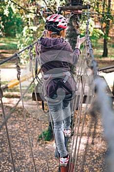 Happy girl, women, climbing gear in an adventure park are engaged in rock climbing on the rope road, arboretum, insurance,