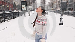 Happy girl in woolen sweater enjoying winter snowy morning.