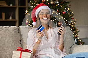 Happy girl in Xmas Santa hat buying Christmas gifts online