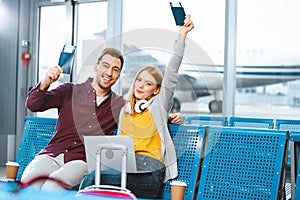Happy girlfriend holding passport above head near smiling boyfriend photo