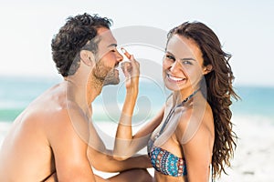 Happy girlfriend putting sunscreen on boyfriends nose