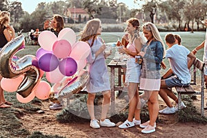 Happy girlfriends conversation together at picnic party outdoor. Scene of a celebrating a birthday at the outdoor park.