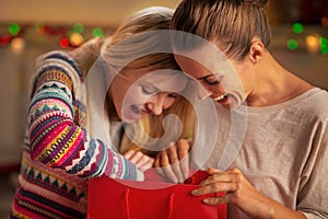 Happy girlfriends looking in shopping bag