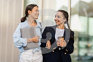 Happy girlfriends walking by street after school, have conversation