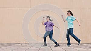 Happy girls dancing outdoors in city street and having fun together