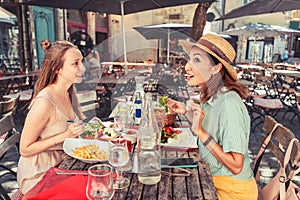 happy girls friends have a fun conversation and talking while a little meal in a terrace restaurant outdoors
