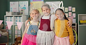 Happy girls, friends and hug with costume in class for dress up or casual day at school together. Portrait of children