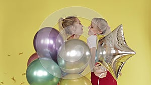 Happy girls having party and dancing on yellow background