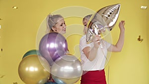 Happy girls having party and dancing on yellow background