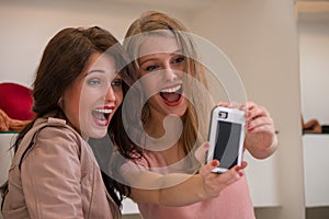 Happy girls indoors photographing selfie while shopping