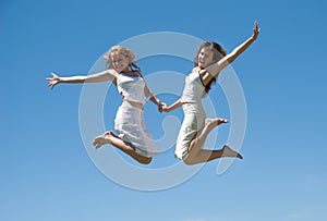 Happy girls jumping against the sky