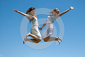 Happy girls jumping against the sky