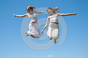 Happy girls jumping against the sky