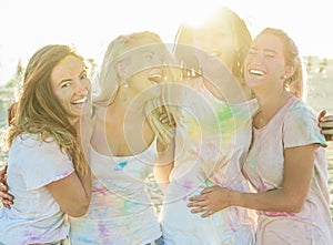 Happy girls making party at holi colors festival in summer time - Young women friends having fun on the beach event at sunset -