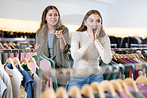 Happy girls pointing finger at new clothes in clothing store