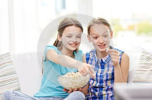 Happy girls with popcorn watching tv at home