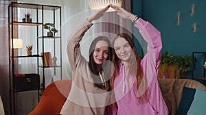 Happy girls siblings making roof gesture sign of hands, new home, ownership, insurance, bank loan