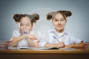 Happy girls sitting at desk on gray background. school concept