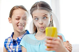 Happy girls with smartphone taking selfie at home