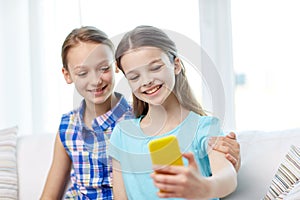 Happy girls with smartphone taking selfie at home