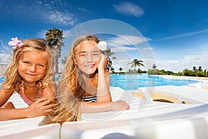 Happy girls sunbathing by outdoor swimming pool