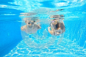 Happy girls swim underwater in pool