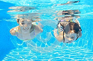 Happy girls swim underwater in pool