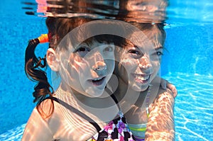 Happy girls swim underwater in pool