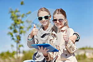 Happy girls with tablet pc showing thumbs up